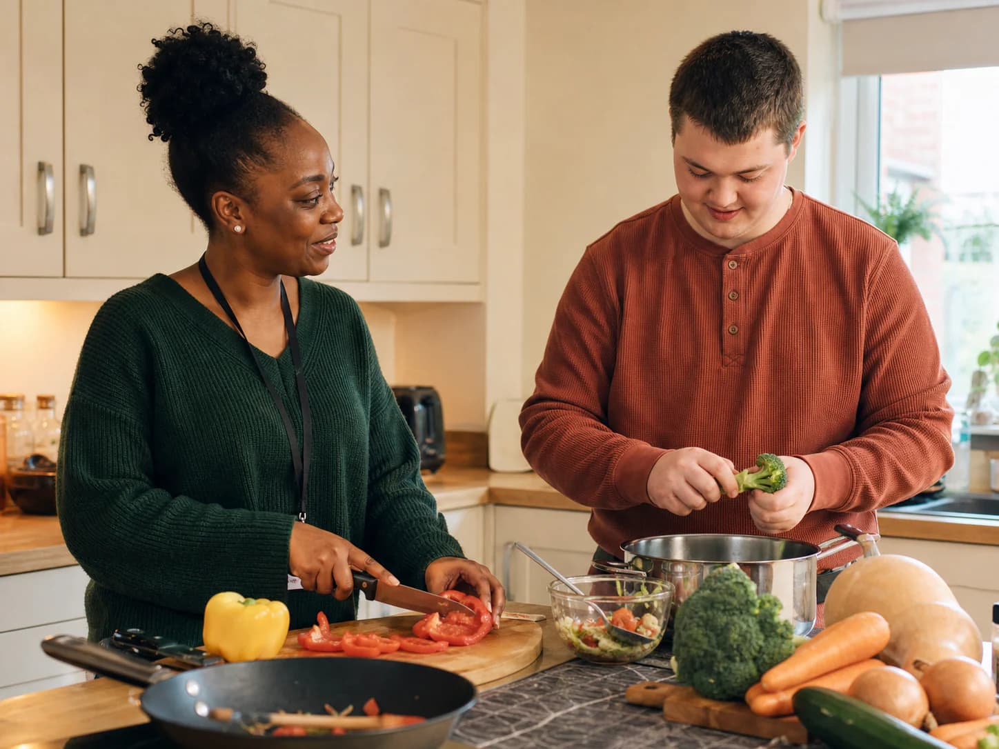 A support worker cooking alongside a young adult in a supported living kitchen